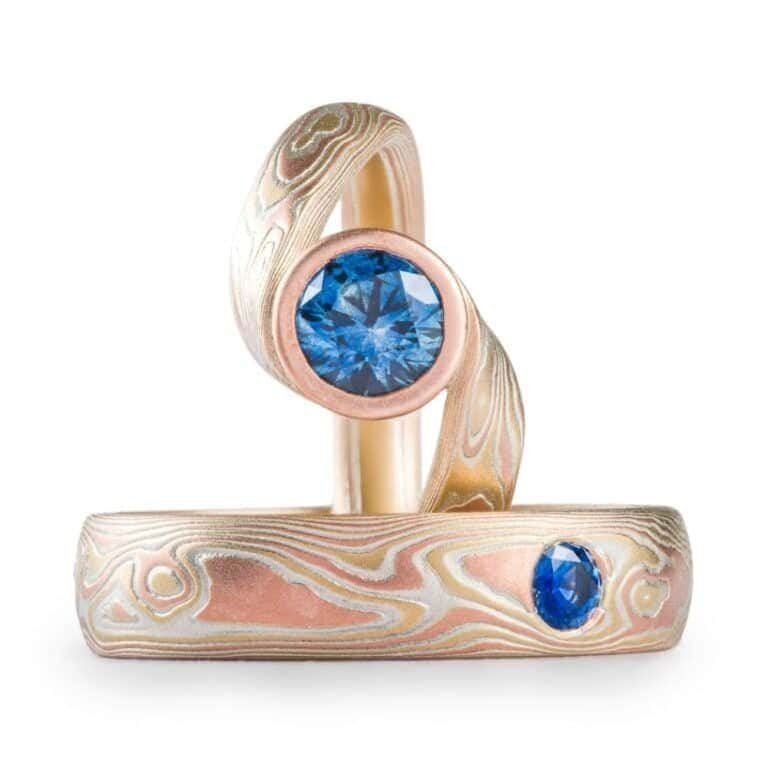 set of matching mokume gane rings with red gold, yellow gold and silver, and matching blue stones