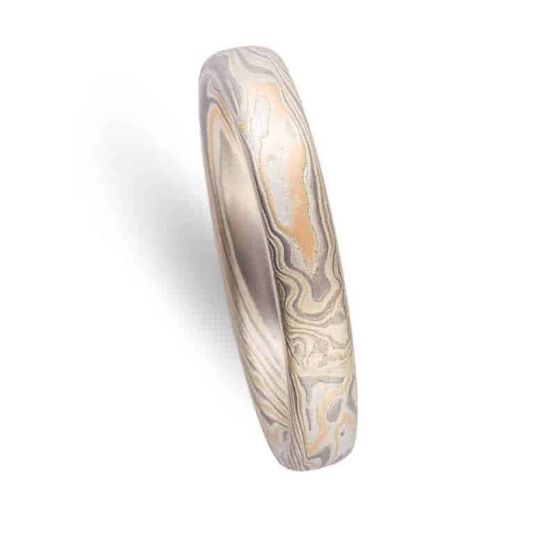 Mokume gane band made in Arn Krebs Flare palette. The Flare palette consists of 14kt Yellow Gold, Palladium, and Sterling Silver. Ring has a low dome profile and smooth finish