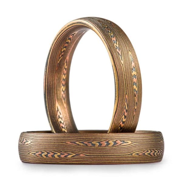 matching mokume gane rings in arn krebs flow pattern with mokume knots, in red gold yellow gold and oxidized silver