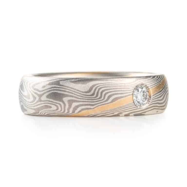 mokume gane band with a flush set salt and pepper diamond and an added yellow gold stratum layer