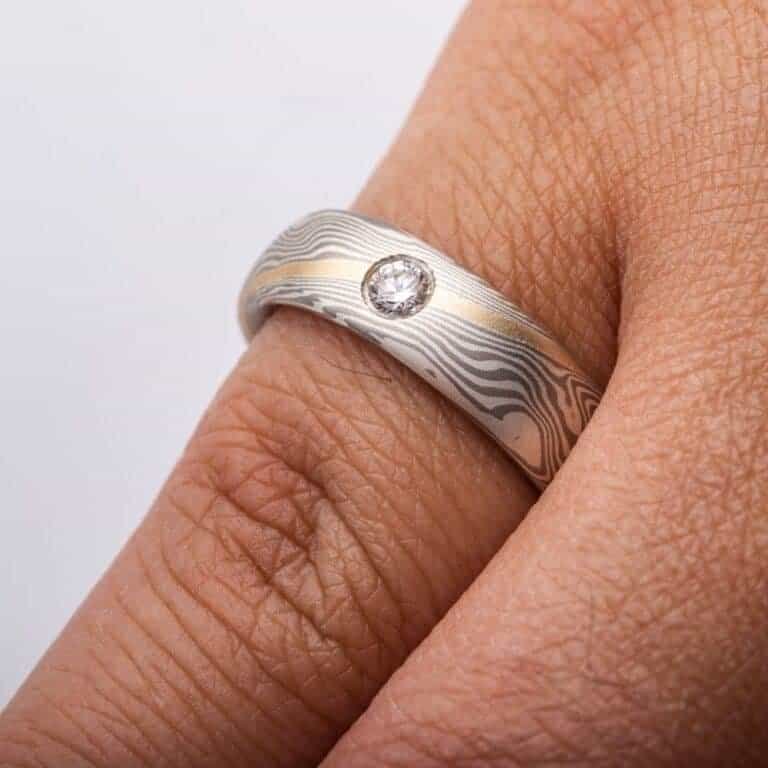 mokume gane band with a flush set salt and pepper diamond and an added yellow gold stratum layer