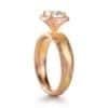 halo diamond ring with a large round stone with many small round stones around the edge with w red gold setting and yellow gold and red gold and silver mokume metal . contemporary looking
