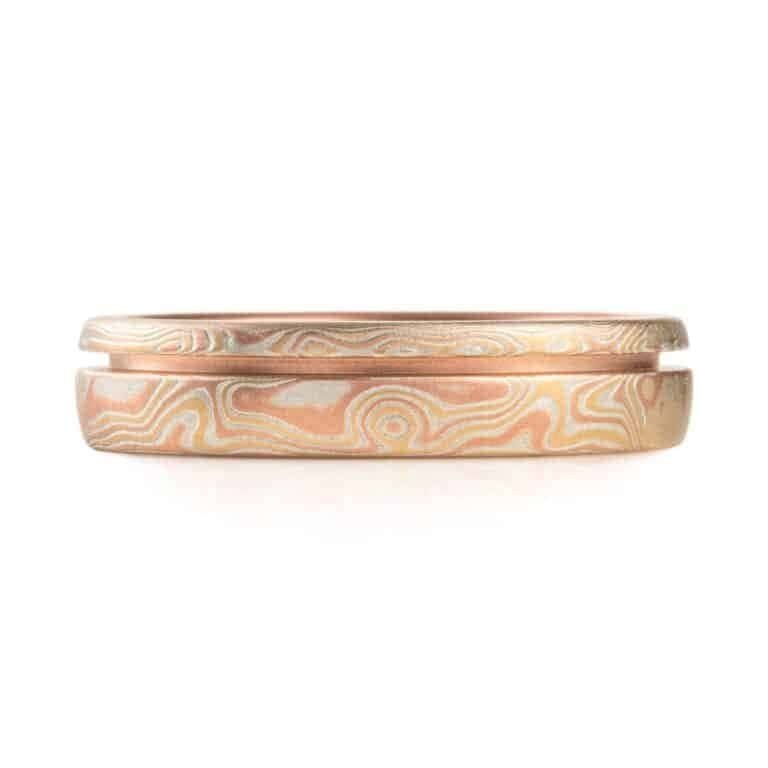 red gold mokume gane ring with a unique inset line, a narrow channel carved into the ring going all the way around, not quite centered, off to one edge