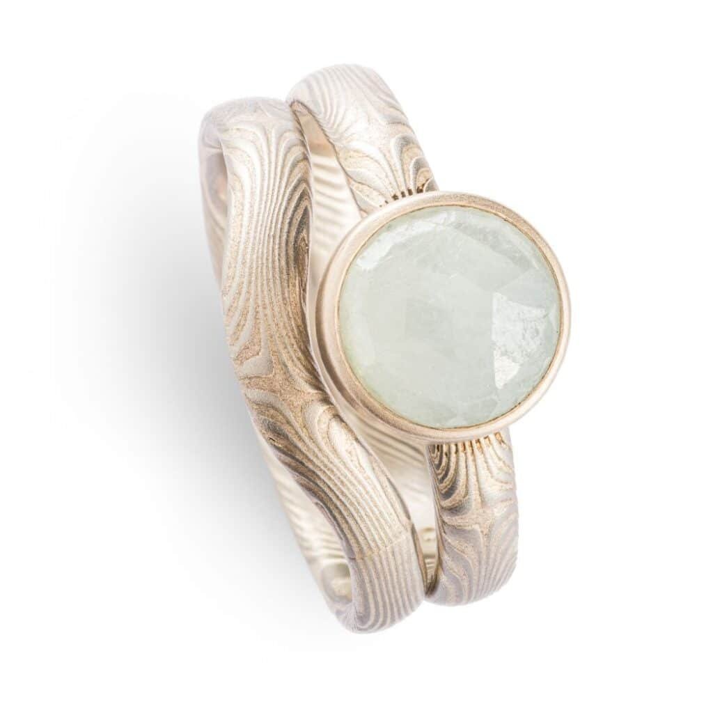 Mokume gane engagement ring with bezel set moonstone bezel setting. 14K white gold palladium sterling silver, with a matching contoured band that curves around the stone