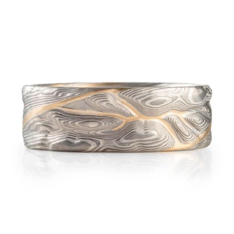 mokume gane pattern ring, topographical style patterning, mostly silver with a yellow gold stratum layer peeking out from under other layers