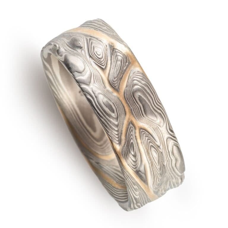 mokume gane pattern ring, topographical style patterning, mostly silver with a yellow gold stratum layer peeking out from under other layers