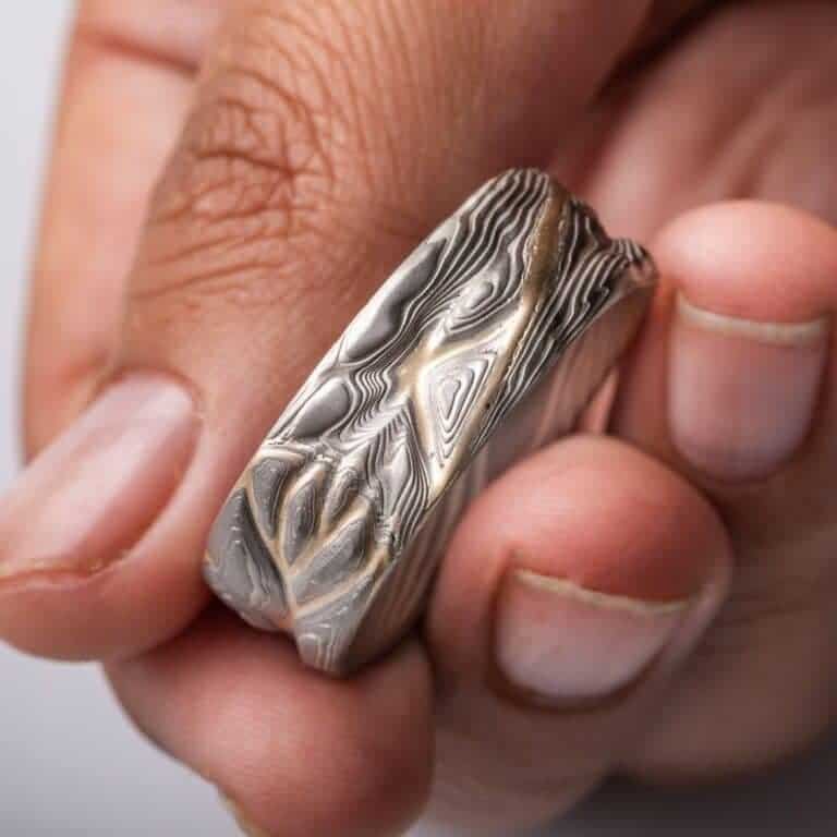 mokume gane pattern ring, topographical style patterning, mostly silver with a yellow gold stratum layer peeking out from under other layers