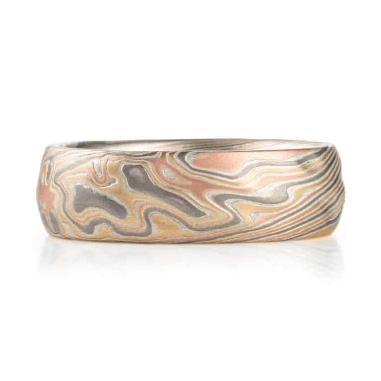 textured twist pattern ring, with a carved surface like rolling waves on the surface of water, overall light looking, made with layers of red and yellow gold, palladium and silver