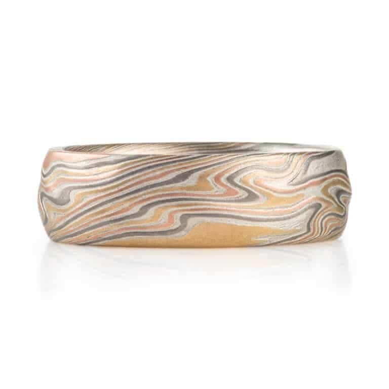 textured twist pattern ring, with a carved surface like rolling waves on the surface of water, overall light looking, made with layers of red and yellow gold, palladium and silver