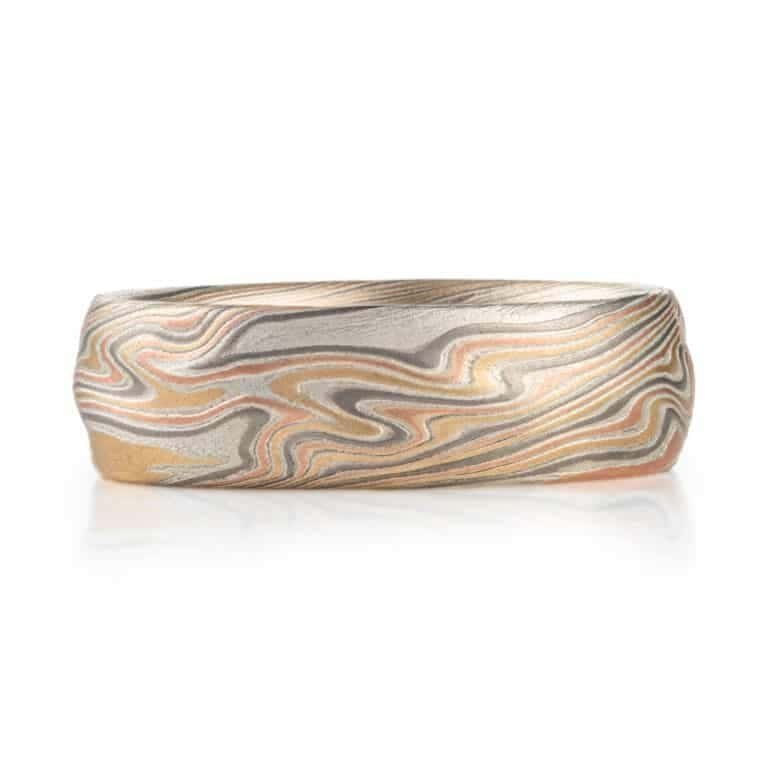 textured twist pattern ring, with a carved surface like rolling waves on the surface of water, overall light looking, made with layers of red and yellow gold, palladium and silver