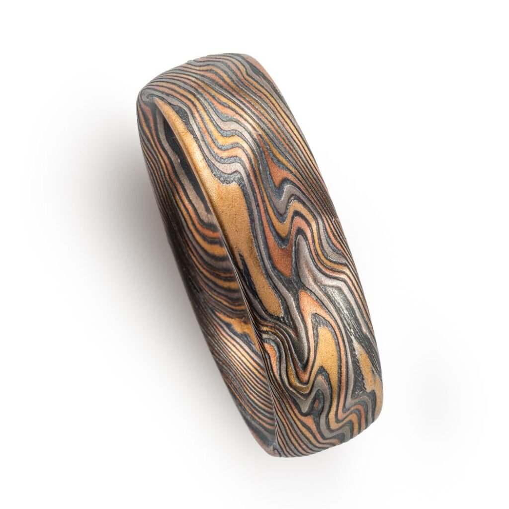 mokume twist pattern ring, made with red and yellow gold, palladium and oxidized silver, with some added texture