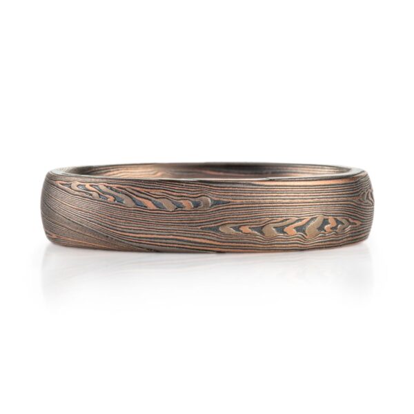 mokume patterned ring made with mainly linear pattern running parallel around the ring, with some areas of increased details, overall darker reddish tone