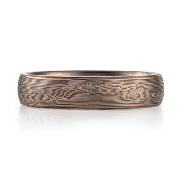 mokume patterned ring made with mainly linear pattern running parallel around the ring, with some areas of increased details, overall darker reddish tone