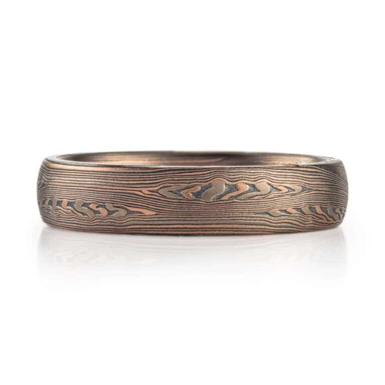 mokume patterned ring made with mainly linear pattern running parallel around the ring, with some areas of increased details, overall darker reddish tone