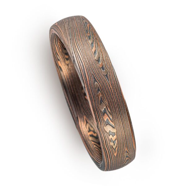 mokume patterned ring made with mainly linear pattern running parallel around the ring, with some areas of increased details, overall darker reddish tone