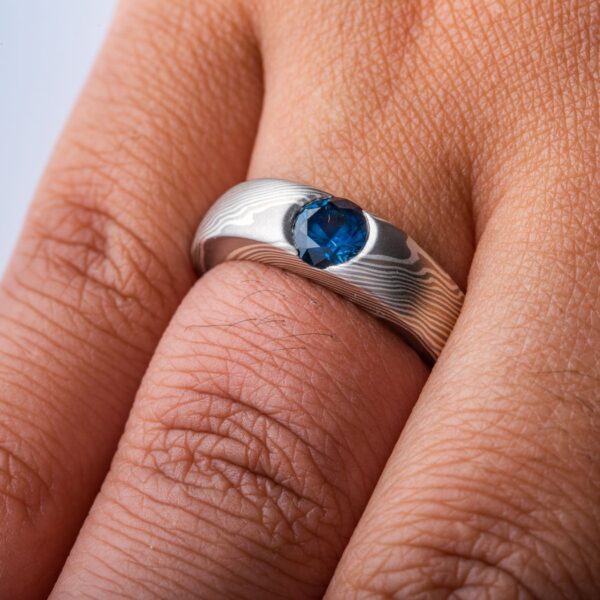 cathedral style ring, slightly thicker towards the top and tapered to the underside, with a round blue stone set into the top