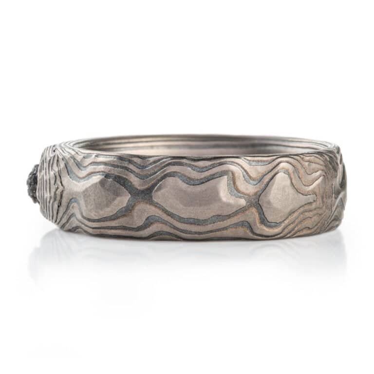 RAW BLACK DIAMONDS in layers of Mokume Gane metal that has striped and lines and ripples. looks like layered earth