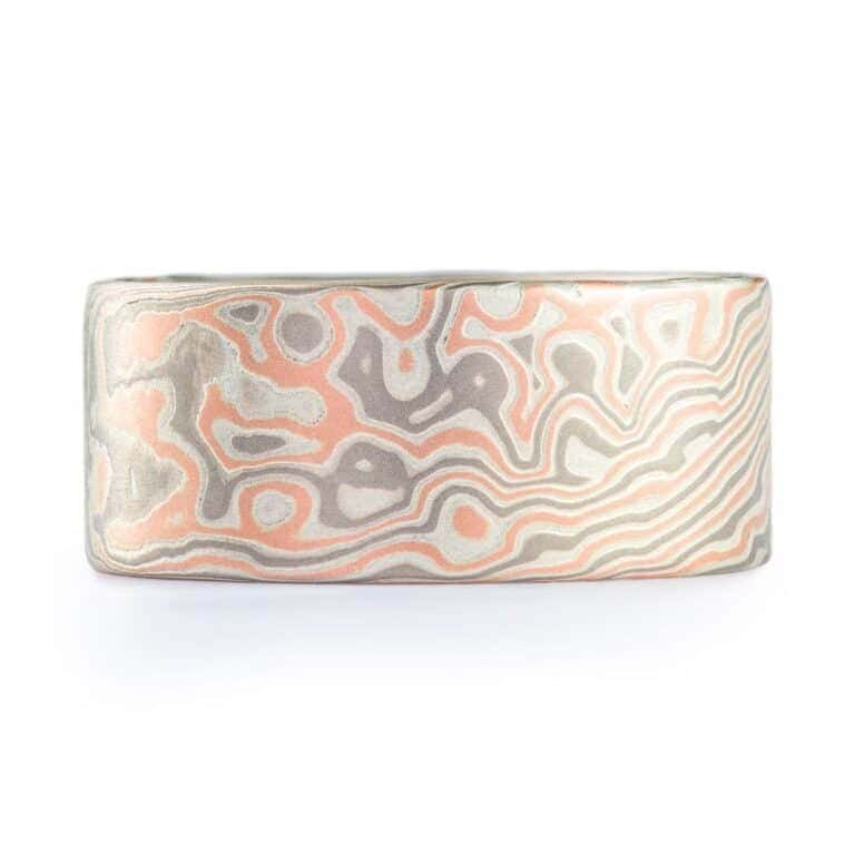 Wide ring with a flat profile, made with red gold, palladium (gray) and silver (light gray), in a twisting and speckled style pattern.  