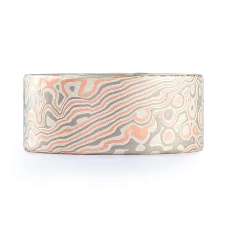 Wide ring with a flat profile, made with red gold, palladium (gray) and silver (light gray), in a twisting and speckled style pattern.  