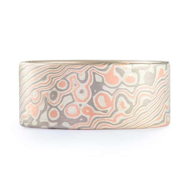 Wide ring with a flat profile, made with red gold, palladium (gray) and silver (light gray), in a twisting and speckled style pattern.