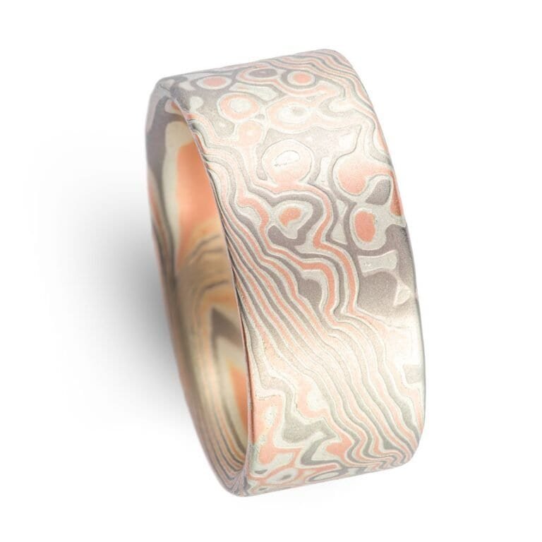 Wide ring with a flat profile, made with red gold, palladium (gray) and silver (light gray), in a twisting and speckled style pattern.  