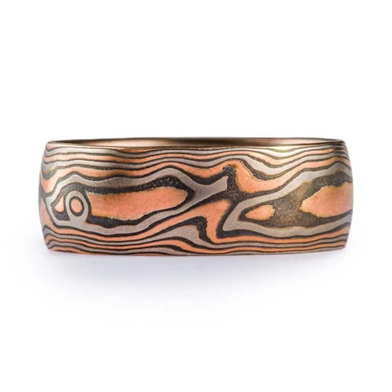 Woodgrain pattern mokume band made with red gold, palladium (gray) and oxidized silver (black).