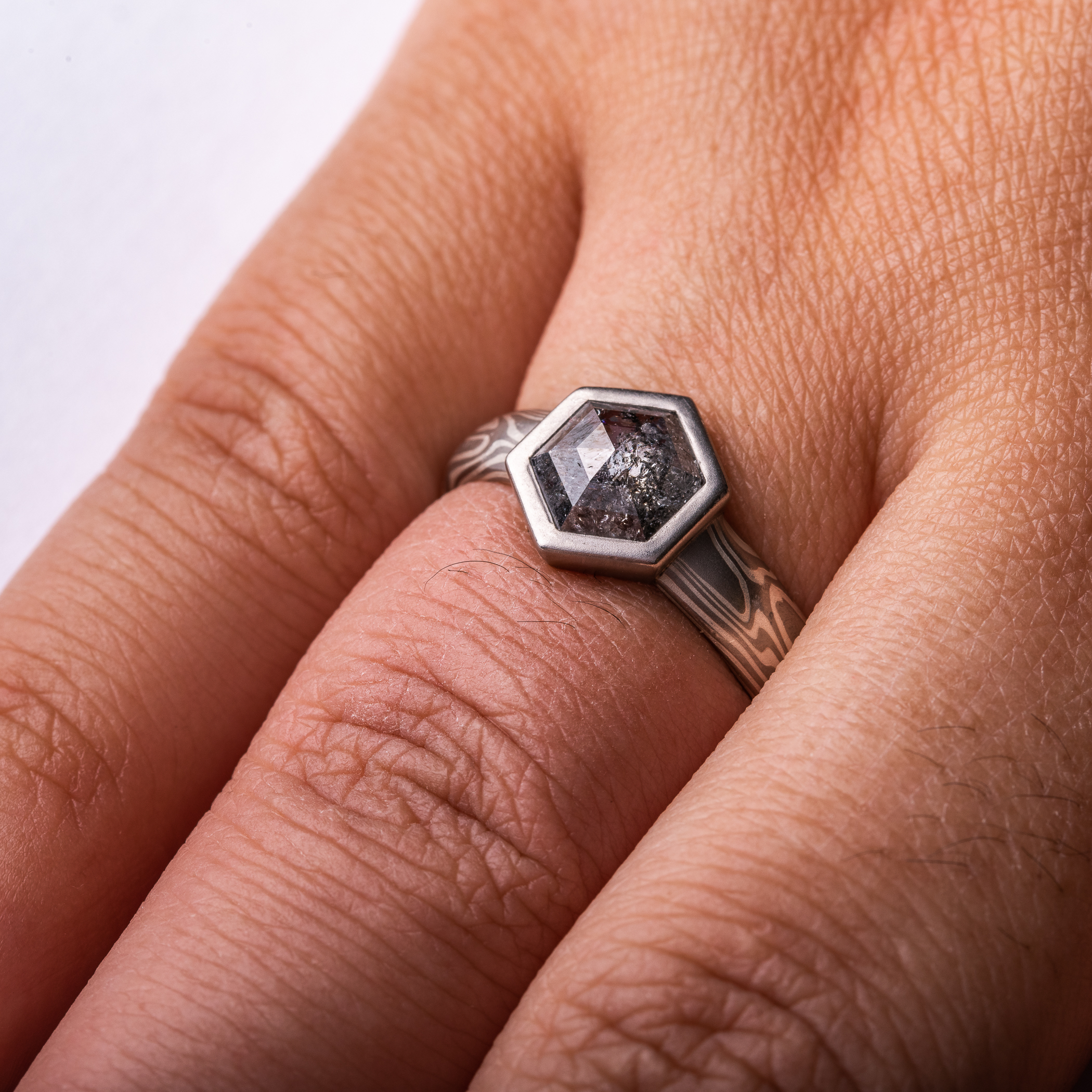 salt and pepper diamond in hexagon cut with hexagon bezel in white gold mokume gane.