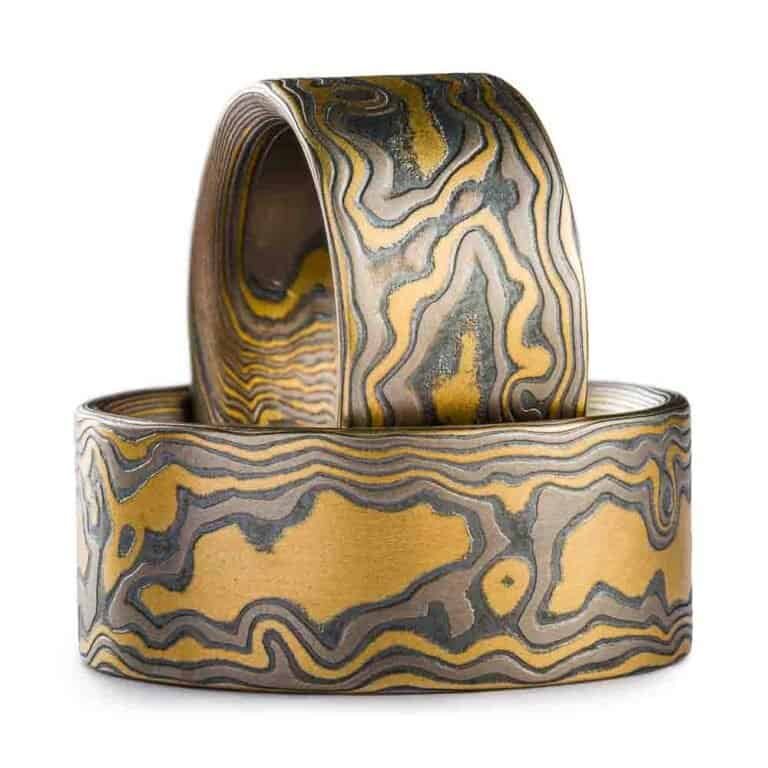 set of two mokume gane rings made in matching woodgrain pattern and flare palette - metals used for the rings are yellow gold, palladium and oxidized silver