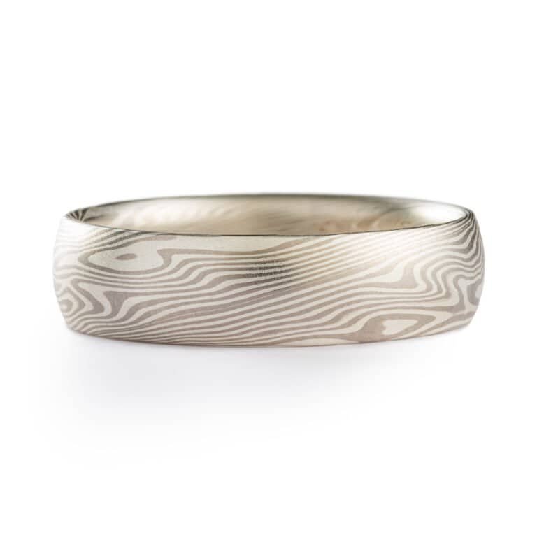 A light and elegant Mokume Gane ring in Twist pattern and Ash Palette has a low dome profile and silvery palette with gentle twisting patterning resembling fog rolling in over a chilly New England morning.