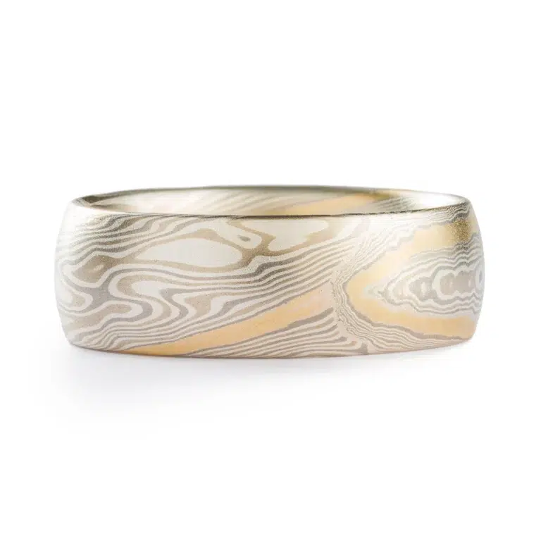 light colored mokume gane twist pattern band with a single stripe of yellow gold running around, smooth finish and domed profile