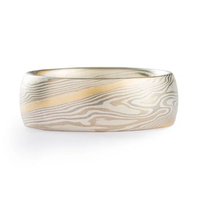 light colored mokume gane twist pattern band with a single stripe of yellow gold running around, smooth finish and domed profile