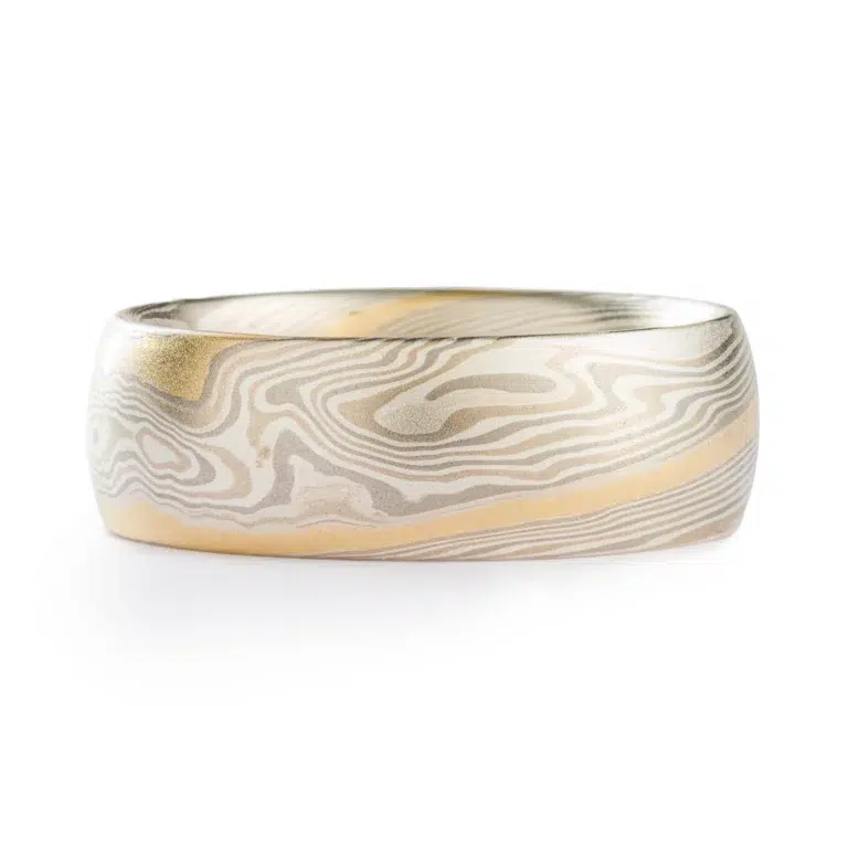 light colored mokume gane twist pattern band with a single stripe of yellow gold running around, smooth finish and domed profile