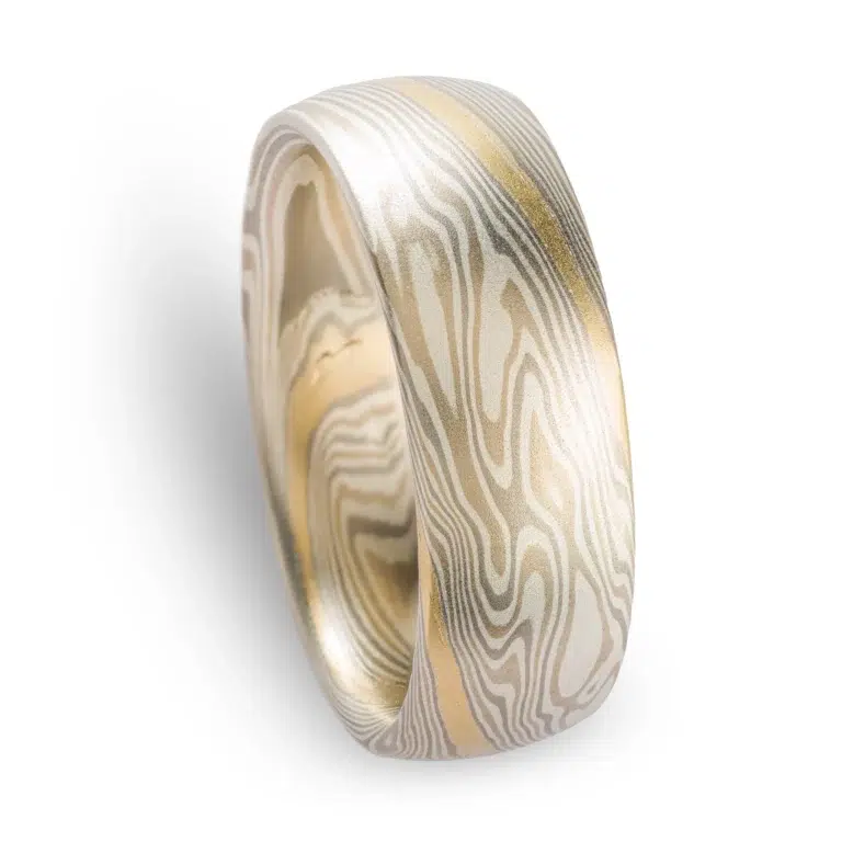 light colored mokume gane twist pattern band with a single stripe of yellow gold running around, smooth finish and domed profile