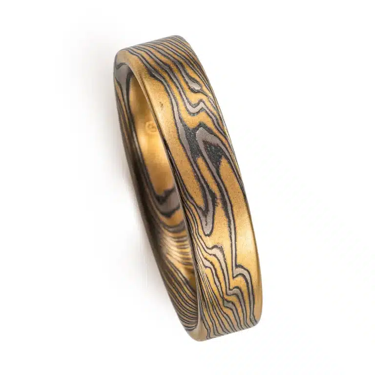 rustic gold mokume gane band with a flat profile ring, high contrast with oxidized silver