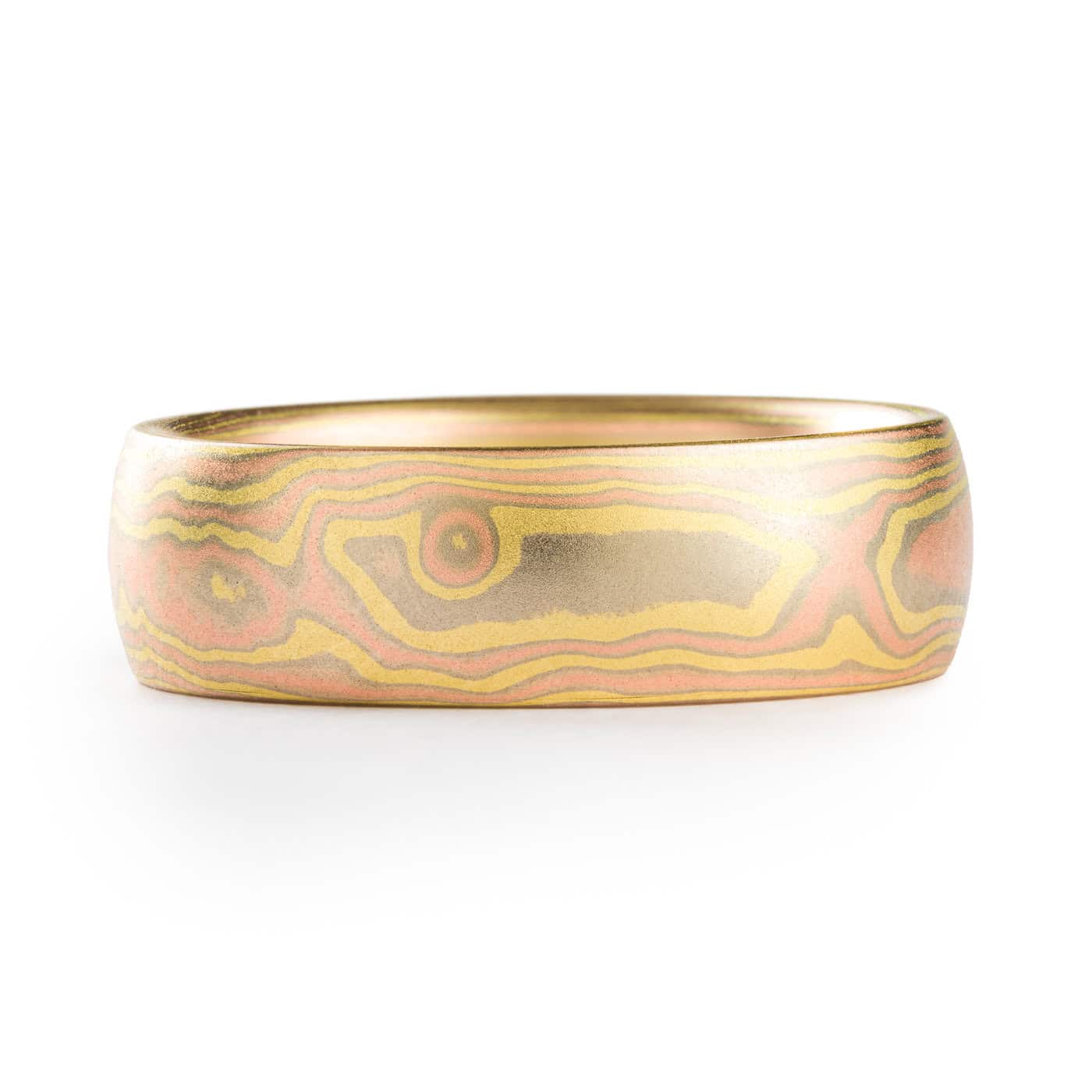 All gold mokume gane ring made in woodgrain pattern, with layers of red gold and yellow gold, and thin layers of white gold in between.