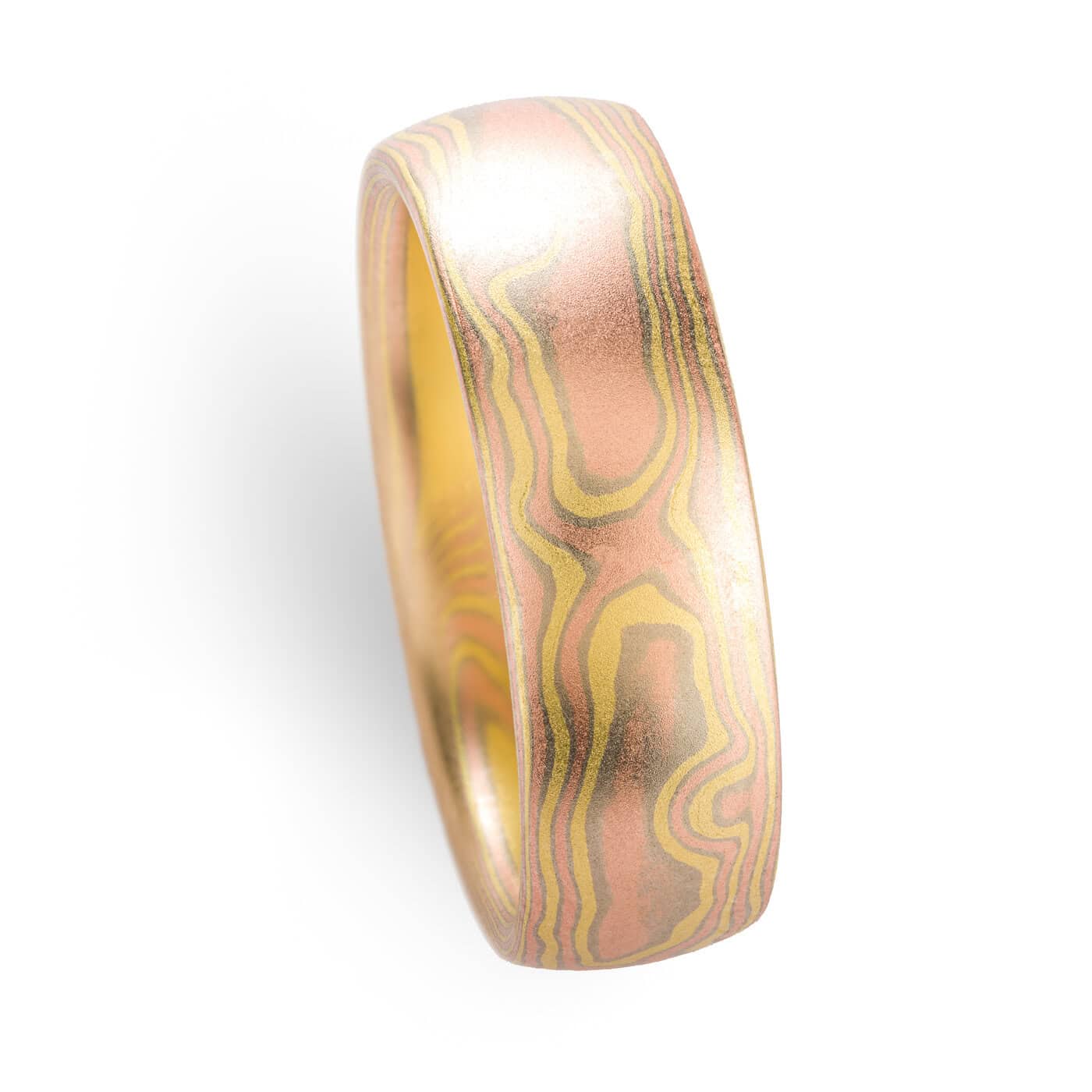 All gold mokume gane ring made in woodgrain pattern, with layers of red gold and yellow gold, and thin layers of white gold in between.