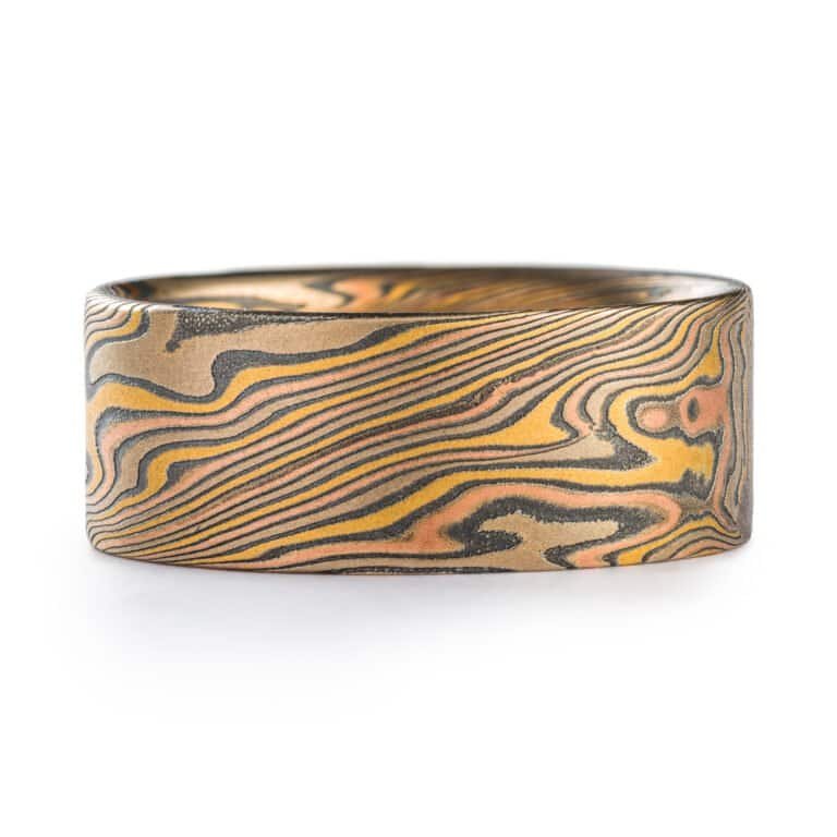 wide mokume gane twist patterned ring with a flat profile, ring is made with layers of red and yellow gold, palladium and oxidized silver