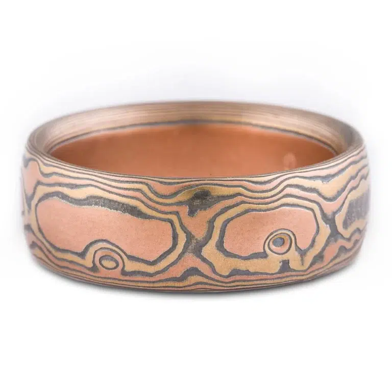 wide mokume gane domed band, made with red gold, yellow gold and oxidized silver, in a woodgrain style pattern
