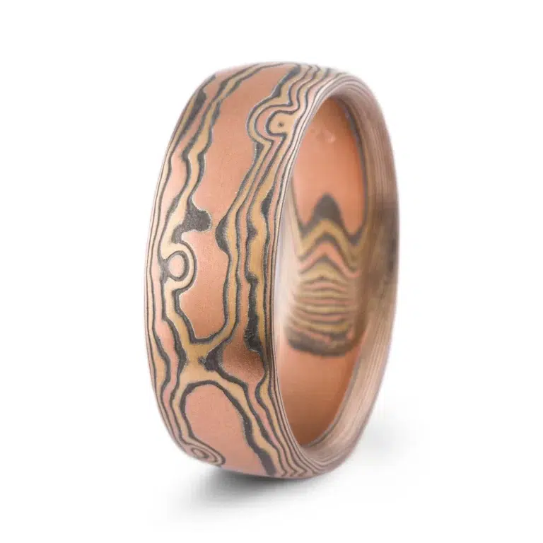 wide mokume gane domed band, made with red gold, yellow gold and oxidized silver, in a woodgrain style pattern