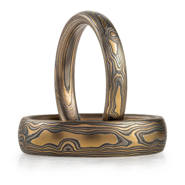 Matching pair of mokume gane rings made to look like woodgrain, made with yellow gold, palladium and silver.