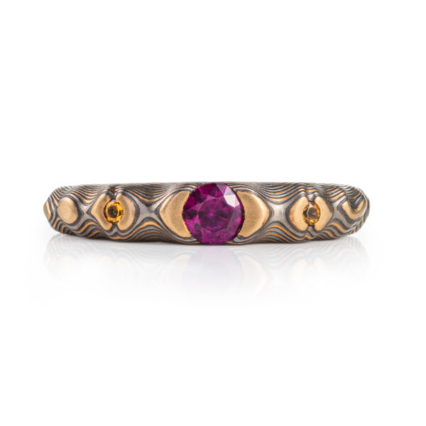 pink purple sapphire with cognac diamonds set in a mokume band of yellow gold, silver and palladium. the stones are set in yellow gold islands