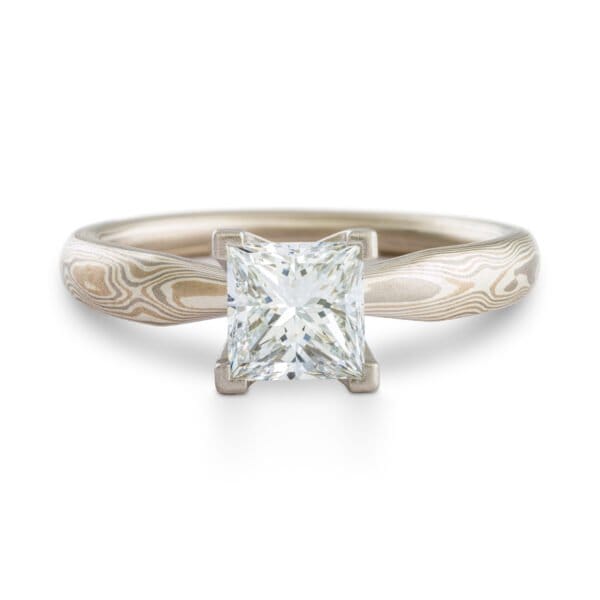 solitaire style mokume gane engagement ring with square diamond set in prongs, ring has an overall silvery palette and a woodgrain style pattern