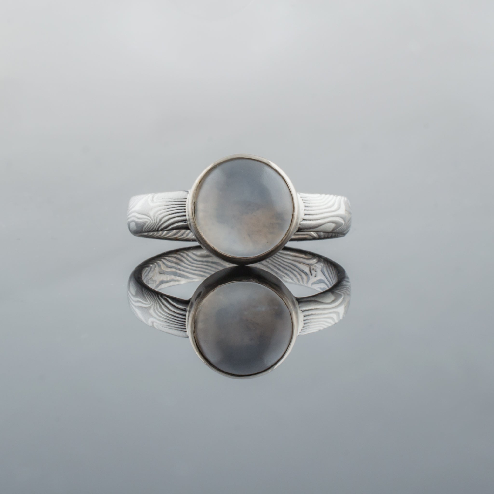 Mokume gane engagement ring with bezel set moonstone bezel setting. 14K white gold palladium sterling silver Beautiful artisan made handmade unique womens engagement ring light blue stone