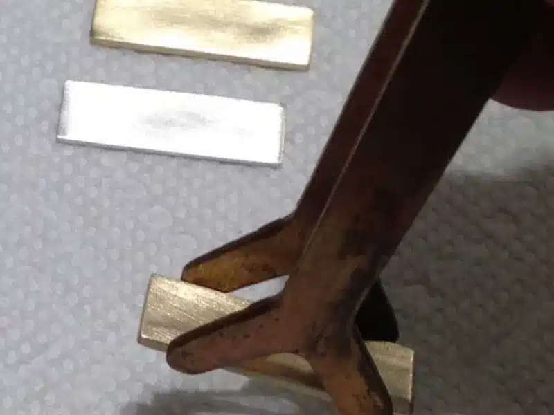 metal tongs holding mokume stock metal slivers
