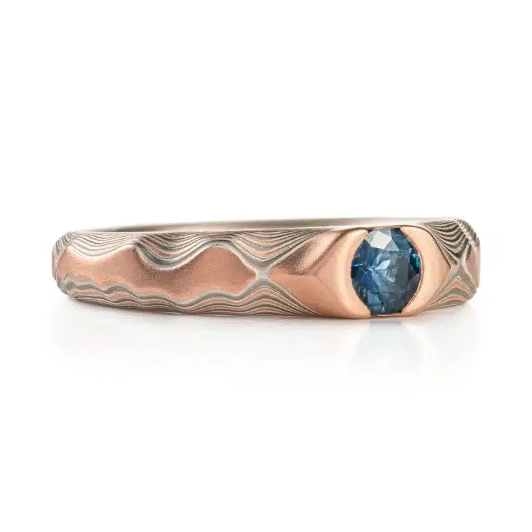 Arn krebs mokume gane ring in guri bori pattern, red gold prominent with a blue sapphire