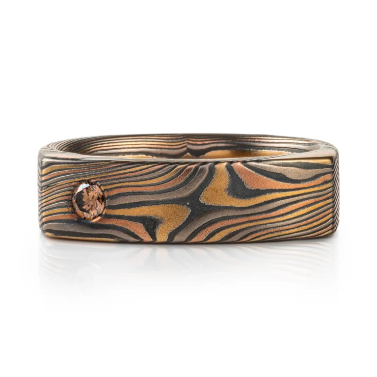 uniquely profiled soft square shaped mokume gane ring with a thicker top section - somewhat similar to a signet style ring, but rectangular, with a small cognac diamond flush set into a corner