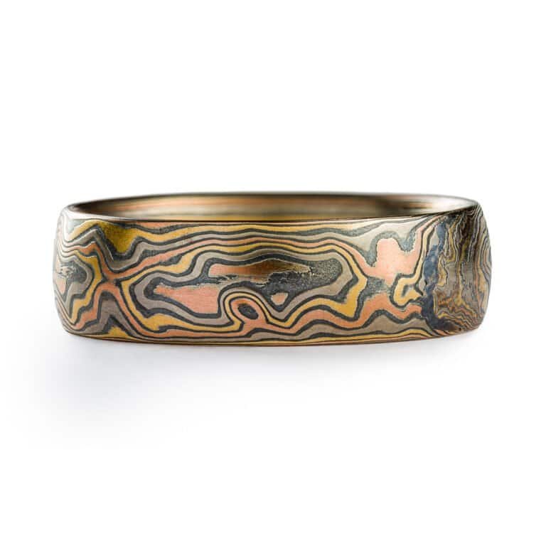 A rustic Woodgrain etched Mokume Gane band with a low dome profile and oxidized finish is made from Firestorm metal.