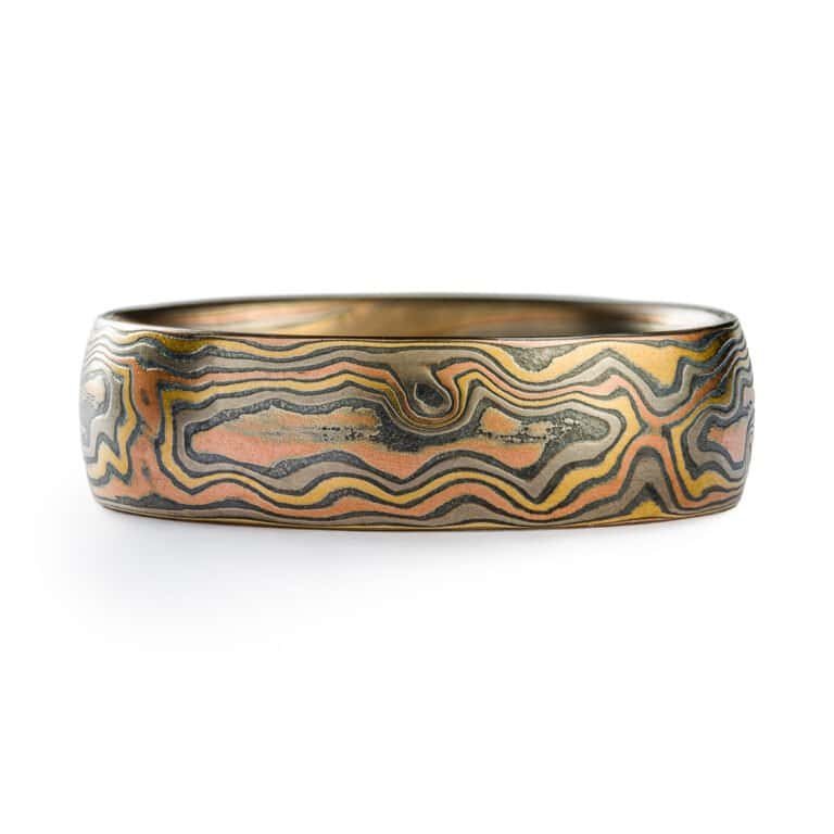 A rustic Woodgrain etched Mokume Gane band with a low dome profile and oxidized finish is made from Firestorm metal.