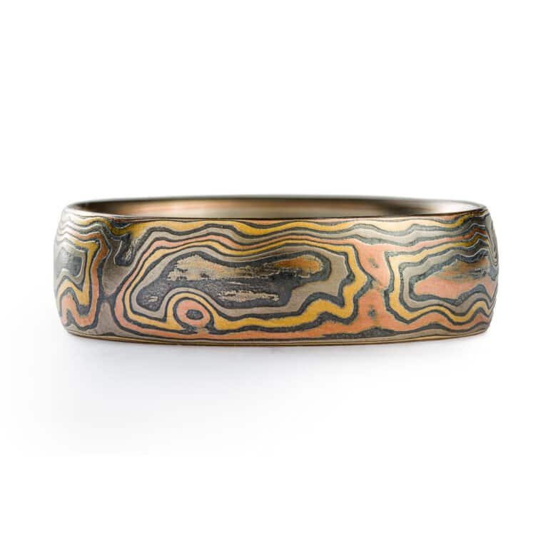 A rustic Woodgrain etched Mokume Gane band with a low dome profile and oxidized finish is made from Firestorm metal.