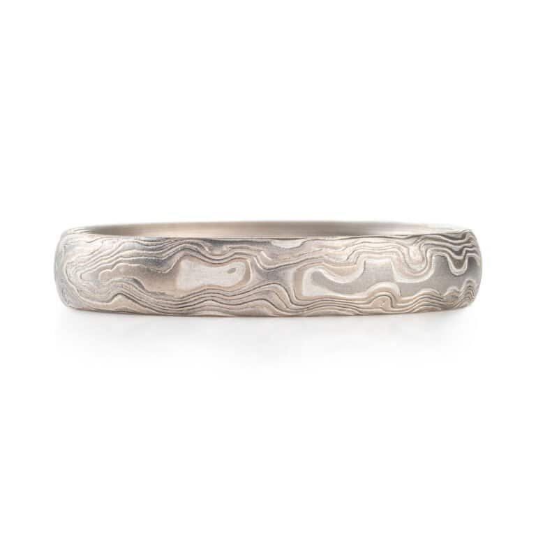 A Mokume Gane band with Woodgrain Pattern and Smoke palette, etched finish, low dome profile, featuring Palladium, 14k white gold, and sterling silver.